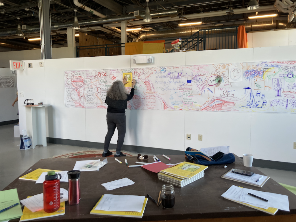 A student working on a wall length mural using markers