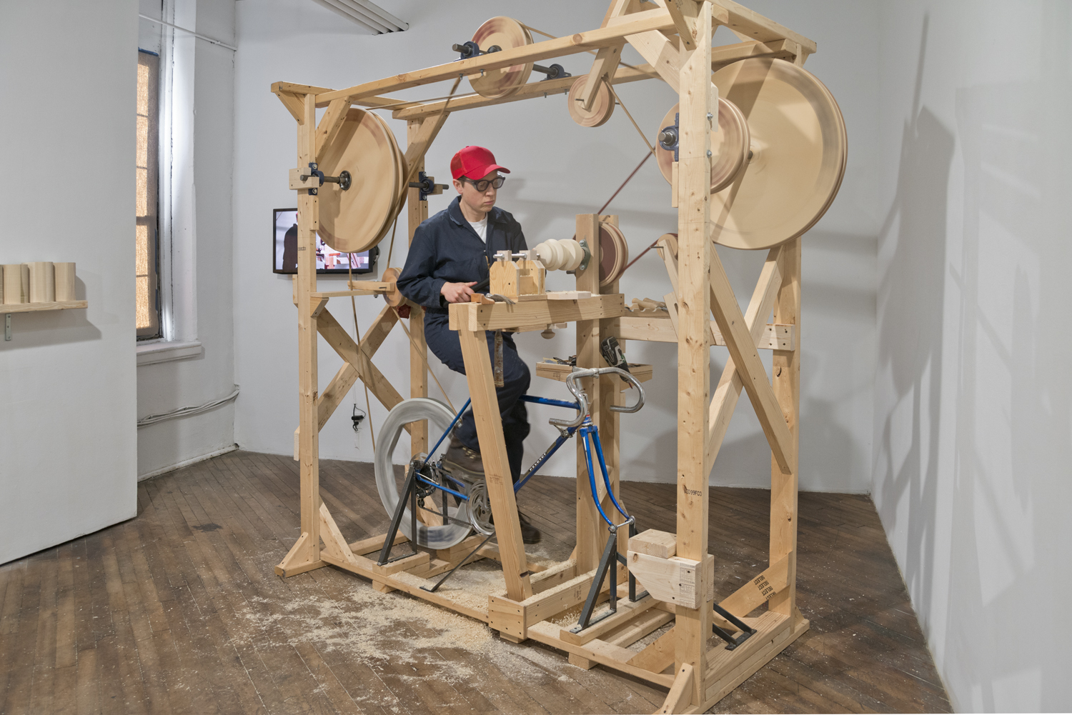 Artist Gina Siepel interacting with large, wooden, mechanical work titled "self made"