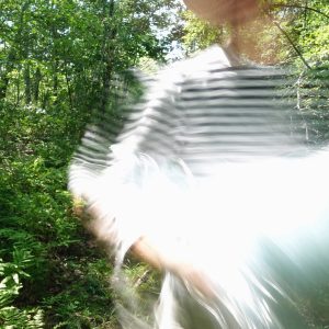 blurry image of a woman in the green forest in Maine